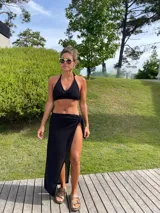 Pareo negro de tejido de punto con abertura lateral y ajuste con lazo.