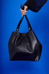 Bolso tipo tote de cuero color marrón claro, con doble asa corta y cierre superior con botón imantado.