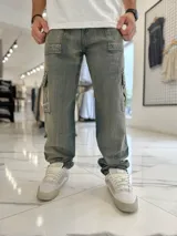 Pantalón cargo de jean azul claro, con bolsillos laterales tipo cargo en las piernas y bolsillos frontales aplicados, de corte ancho y holgado.
