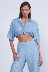 Camisa celeste de tejido con textura, corte cropped, cuello camisero y mangas cortas.