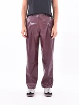 Pantalon de cuero sintético en color bordó, de corte recto y tiro medio. Presenta costuras decorativas en la zona de la cadera y rodillas, con cierre frontal y bolsillos laterales.