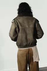 Cazadora de efecto ante con cuello de solapa y aplicación de pelo sintético desmontable. Presenta manga larga, trabillas en los hombros, bolsillos frontales con solapa y cierre de cremallera con botones ocultos.