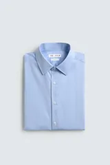 Camisa de manga larga, color blanco, con cuello italiano y corte slim fit. Presenta cierre frontal de botonadura y puños con botón.