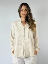 Camisa color mostaza con volados desflecados a lo largo de la botonadura frontal, cuello mao y mangas largas con puños abotonados.