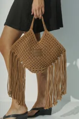 Bolso de mano marrón claro, tejido a crochet con flecos largos y asas cortas.