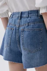 Short de jean azul de calce holgado, tiro alto, piernas anchas con tablas y ruedo desflecado.