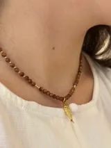 Collar de cuentas de piedra del sol marrón con destellos, con dije colgante en forma de pez con baño dorado.