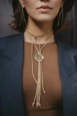 Gargantilla de gamuza marrón con dije de espiral dorado y cuentas de bronce.
