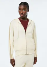 Campera de punto con cierre frontal, capucha con cordones ajustables y bolsillos tipo canguro. Presenta un diseño de manga larga con detalles acanalados en los laterales y puños.