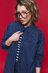 Camisa de manga larga con diseño de rayas verticales y horizontales en color marrón. Presenta un corte oversize con hombros caídos, cuello clásico y cierre frontal con botones.