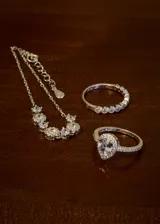 Conjunto de joyería de tres piezas en plata 925 y zirconias, compuesto por una pulsera con cadena y zirconias colgantes, un anillo medio sin fin con zirconias y un anillo solitario con zirconias en corte gota y pavé lateral.
