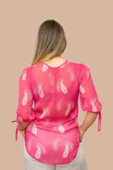 Blusa amarilla de gasa estampada con arabescos blancos, de corte irregular y mangas tres cuartos con lazo.