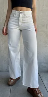 Pantalón jean de tiro alto color blanco, corte recto y pierna ancha.