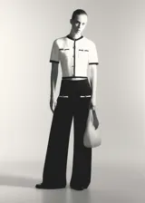 Pantalon de punto fino color negro, de corte recto y tiro medio. Presenta cintura elástica, dos bolsillos delanteros con ribete en contraste color blanco y botones decorativos dorados.