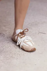 Zuecos de cuero color beige, con cordones marrones y verdes, y detalles de costuras.