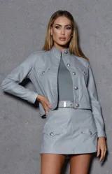 Chaqueta gris de cuero sintético con cuello mao, cierre frontal con botones metálicos y bolsillos con solapa en el pecho.