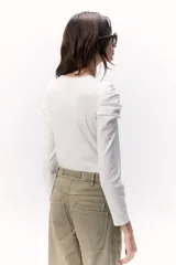 Remera de rib color crudo, con cuello redondo y mangas largas abullonadas y fruncidas en los hombros.