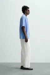 Cárdigan celeste de tejido de algodón con estructura tipo waffle. Tiene cuello solapa, manga corta y cierre frontal con botones.