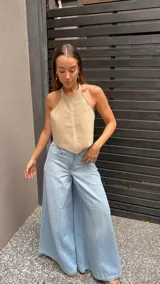 Top halter color beige, estilo chaleco corto, con cuello alto y bordes festoneados con costura decorativa.