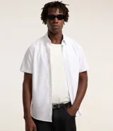 Camisa de manga corta confeccionada en mezcla de poliéster y fibra de bambú, con diseño de rayas finas, cuello con solapa abotonada, cierre frontal de botones y bolsillo en el pecho.