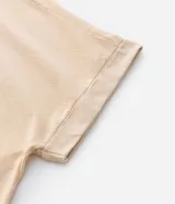 Blusa de corte boxy color beige con rayas finas horizontales, cuello redondo y mangas cortas con dobladillo. Presenta un delicado bordado de cajú en el pecho.