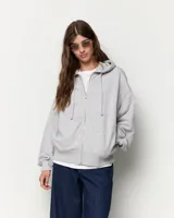 Buzo oversize gris con cierre frontal completo, capucha con cordón ajustable y bolsillos delanteros tipo canguro.
