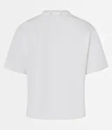 Remera blanca de algodón con cuello redondo y corte boxy, con apliques de flores de tejido en relieve en la zona del pecho.