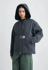 Campera con capucha Carhartt WIP modelo Mitch, color negro desgastado, confeccionada en lona de algodón con forro interior de pelo. Cuenta con cierre frontal bidireccional, bolsillos frontales tipo parche y etiqueta cuadrada de la marca.