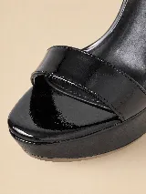 Sandalias de plataforma y taco alto de charol negro, con tira delantera ancha, tira ajustable al tobillo con hebilla dorada y talón cerrado.