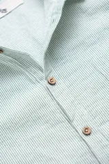 Camisa de manga corta celeste con rayas verticales blancas, cuello clásico, cierre frontal con botones y bolsillo de parche en el pecho.