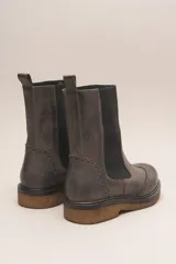 Bota tipo Chelsea de cuero vacuno color suela, con diseño brogue en la puntera y laterales. Presenta paneles elásticos laterales en color marrón oscuro, tirador trasero y suela de goma con plataforma.
