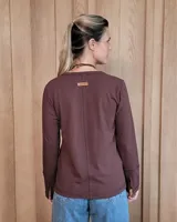 Remera blanca de manga larga con cuello en V y costuras decorativas en contraste. Incluye un lazo ajustable en el cuello con herraje metálico circular.