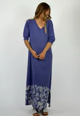 Vestido largo azul con cuello en V y mangas 3/4. Tiene un estampado difuminado en el ruedo.