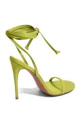 Sandalias de tacón fino color amarillo con tiras delgadas y cierre con lazo en el tobillo.