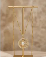 Collar de cadena tipo soga en tono dorado con dije circular compuesto por anillos concéntricos incrustados con circonias y una perla central.