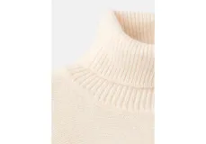 Poncho de tejido de punto color marfil, con cuello alto vuelto y diseño amplio con aberturas para los brazos.