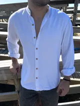 Camisa blanca de lino con cuello mao, manga larga con puños abotonados y cierre frontal con botones de madera.