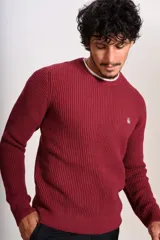 Sweater de punto grueso con cuello redondo y manga larga. Presenta un diseño de tejido acanalado y el logo de la marca bordado en el pecho.