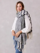 Bufandón de tejido soft con diseño de rayas horizontales en tonos gris y blanco, con terminación de flecos largos en los extremos.