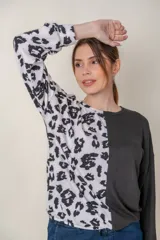 Buzo de manga larga con cuello redondo, combinado en dos tonos: negro liso en la mitad derecha y estampado animal print blanco y negro en la mitad izquierda.