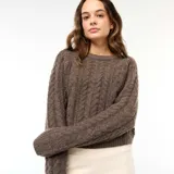 Sweater de punto con diseño trenzado, cuello redondo y mangas largas, de corte holgado y textura suave.