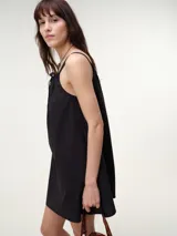 Vestido corto fluido de popelina de algodón en color negro, con diseño liviano, tirantes finos regulables con moña y bolsillos laterales.