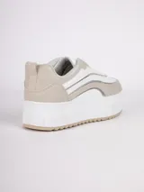 Zapatilla de plataforma con diseño de recortes en tonos blanco, beige y detalles metalizados plateados. Cuenta con suela texturizada y cierre mediante cordones.