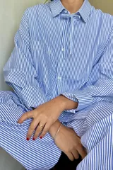 Conjunto de pijama azul a rayas blancas, compuesto por una camisa de manga larga con cuello y un pantalón largo.