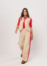 Chaleco beige con escote en V, sin mangas y cierre frontal con botones. Presenta pespuntes en color rojo y logo bordado en la espalda.