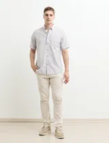 Camisa de manga corta a rayas verticales celestes y blancas, con cuello abotonado y corte clásico.