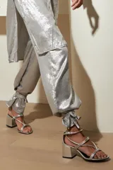 Pantalón de vestir color bronce con textura brillante, corte holgado, cintura alta y tobillos ajustados.