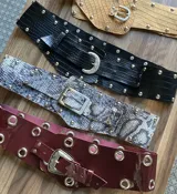 Cinto de cuero con hebilla metálica y diseño texturizado símil piel de cocodrilo, serpiente o charol.