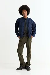 Campera tipo bomber color tostado, con cierre frontal, cuello, puños y ruedo de tejido elástico acanalado. Presenta costuras horizontales en la parte superior del pecho.