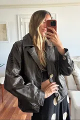 Campera tipo bomber confeccionada en cuero ovino de color chocolate, con forro interior. Presenta cuello con solapa, cierre frontal con botones de guampa y detalles de pasamanería en cuero marrón en las mangas.